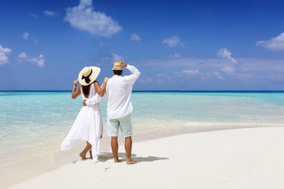 Rear view of couple looking at sea against sky