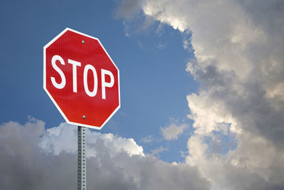 Low angle view of stop sign against cloudy sky