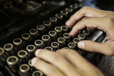 Cropped hands of person typing on vintage typewriter