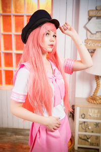 Full length of young woman holding pink while standing against wall