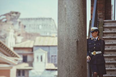 Portrait of young woman standing against built structure