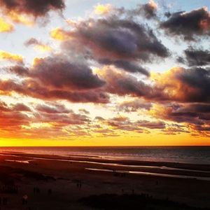 Scenic view of sea against dramatic sky during sunset