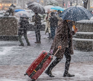 Full length of man holding umbrella in city during winter