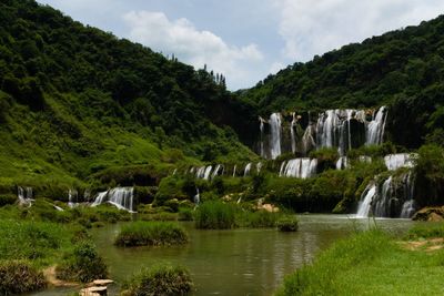 Scenic view of waterfall against sky