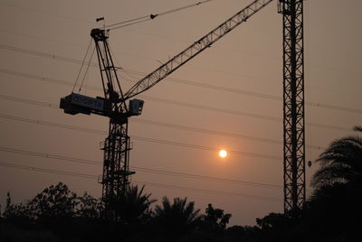 Low angle view of silhouette electricity pylon against sky during sunset