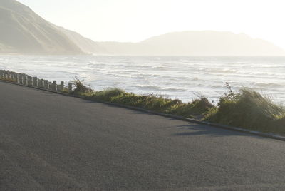 Scenic view of road by mountains against sky