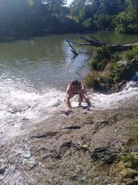 Full length of man surfing on rock in lake