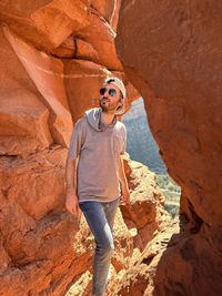 Portrait of young man standing against rock formations