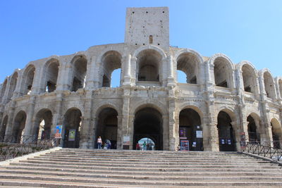 Tourists at historical building against clear blue sky