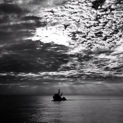 Silhouette boat sailing on sea against sky