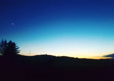 Silhouette trees against clear blue sky