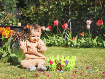 Happy baby girl with easter chocolate egg on the lawn.