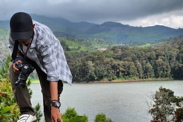 mountain, lifestyles, sky, leisure activity, standing, men, rear view, mountain range, casual clothing, tranquil scene, scenics, tranquility, cloud - sky, nature, lake, beauty in nature, water, tree