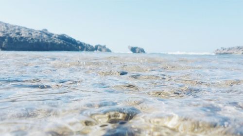 Surface level of calm sea against clear sky