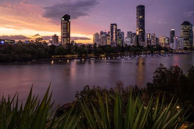 High angle view of river in illuminated city against sky during sunset