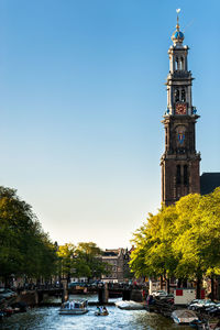 Tower amidst trees and buildings against sky