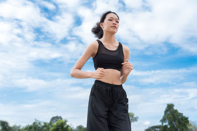 Low angle view of woman standing against sky