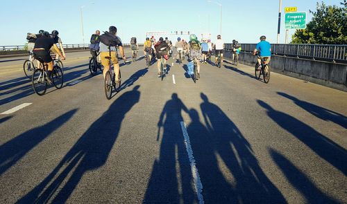 Rear view of people riding bicycle on road