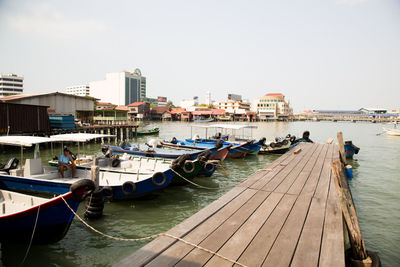 Boats moored in sea by buildings against clear sky