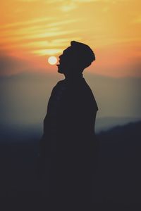 Silhouette man standing against orange sky during sunset