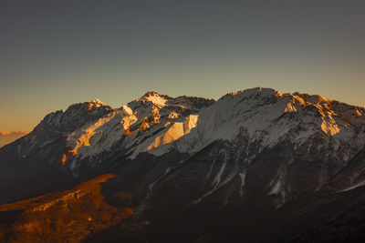 Scenic view of snowcapped mountains against clear sky during sunset