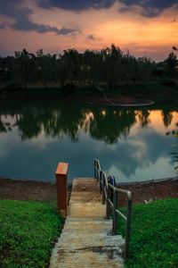 Pier on lake against sky during sunset