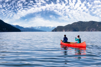 People in boat on lake against sky