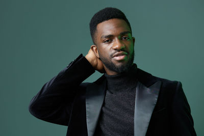 Portrait of young man standing against gray background