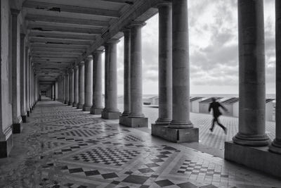 Rear view of woman walking on colonnade