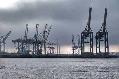 Cranes at commercial dock against sky