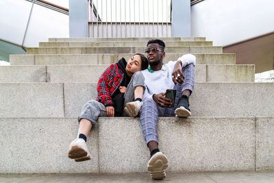 Full length of happy friends sitting on staircase