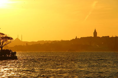 Scenic view of river by buildings against sky during sunset