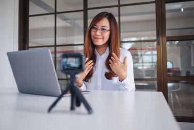 Portrait of young woman using phone on table