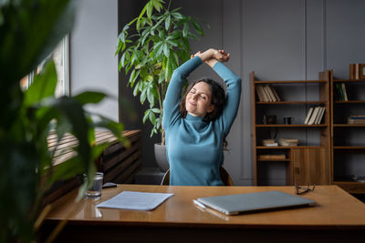 Joyful woman stretching relaxed with closed eyes enjoy break after work done sit with closed laptop