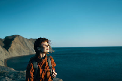 Woman looking at sea against clear sky