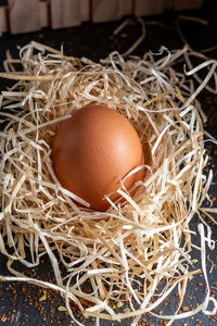 Golden egg in a nest on old wooden texture - fresh egg over straw