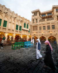 People walking on street against buildings in city