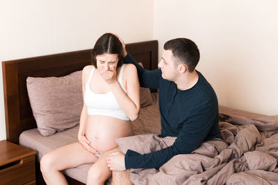 Young couple sitting on bed at home