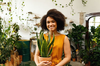 Portrait of smiling young woman standing against plants