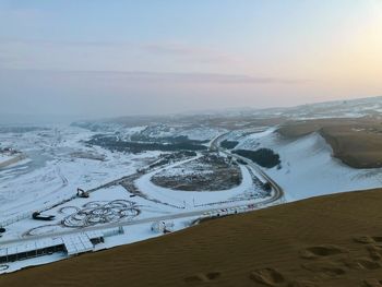 Aerial view of snowcapped landscape against sky during sunset