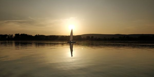 Scenic view of lake against sky during sunset with sail