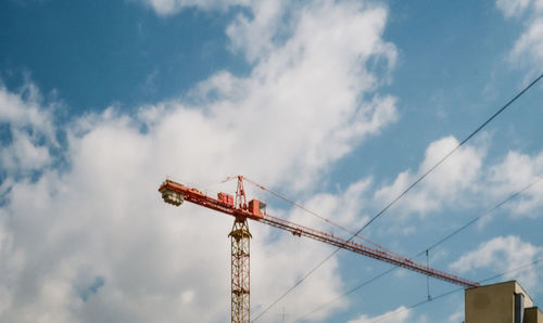 Low angle view of crane at construction site against sky