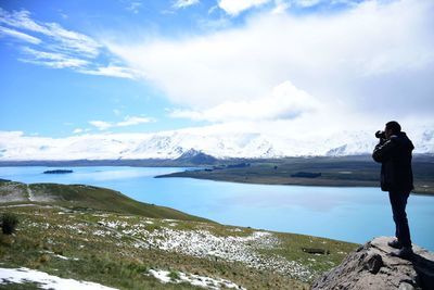 Man photographing lake against sky