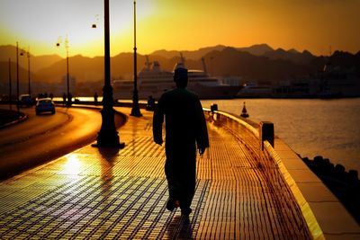 Silhouette man walking on sidewalk during sunset