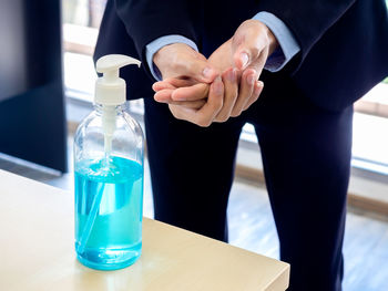 Close-up of man holding glass bottle on table