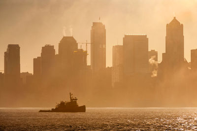 Tug boat on elliott bay against buildings in city during foggy weather