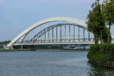 Bridge over river in city against sky