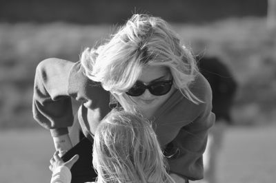 Mother wearing sunglasses while looking at daughter