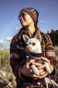 Smiling asian strong woman sits in sun with two small dogs at beach