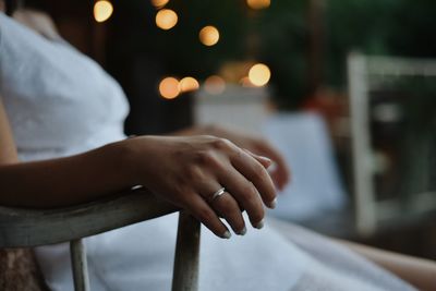 Midsection of woman sitting on seat with wedding ring